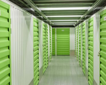 Background shot of green metal door closed on latch with lock on leading to self storage unit at warehouse, copy space
