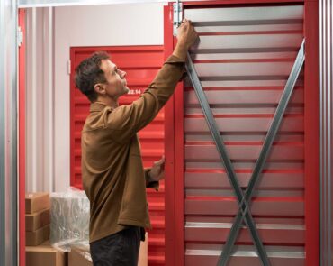 Man opening door of self-storage unit to place boxes with belongings inside