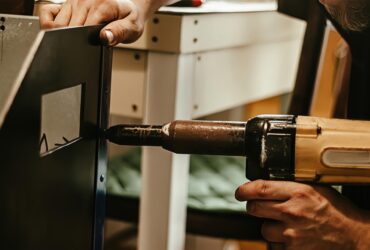 Male worker uses electric riveting gun. Hand holding  riveting machine and placing rivets. Working workshop of carpenter or mechanic.